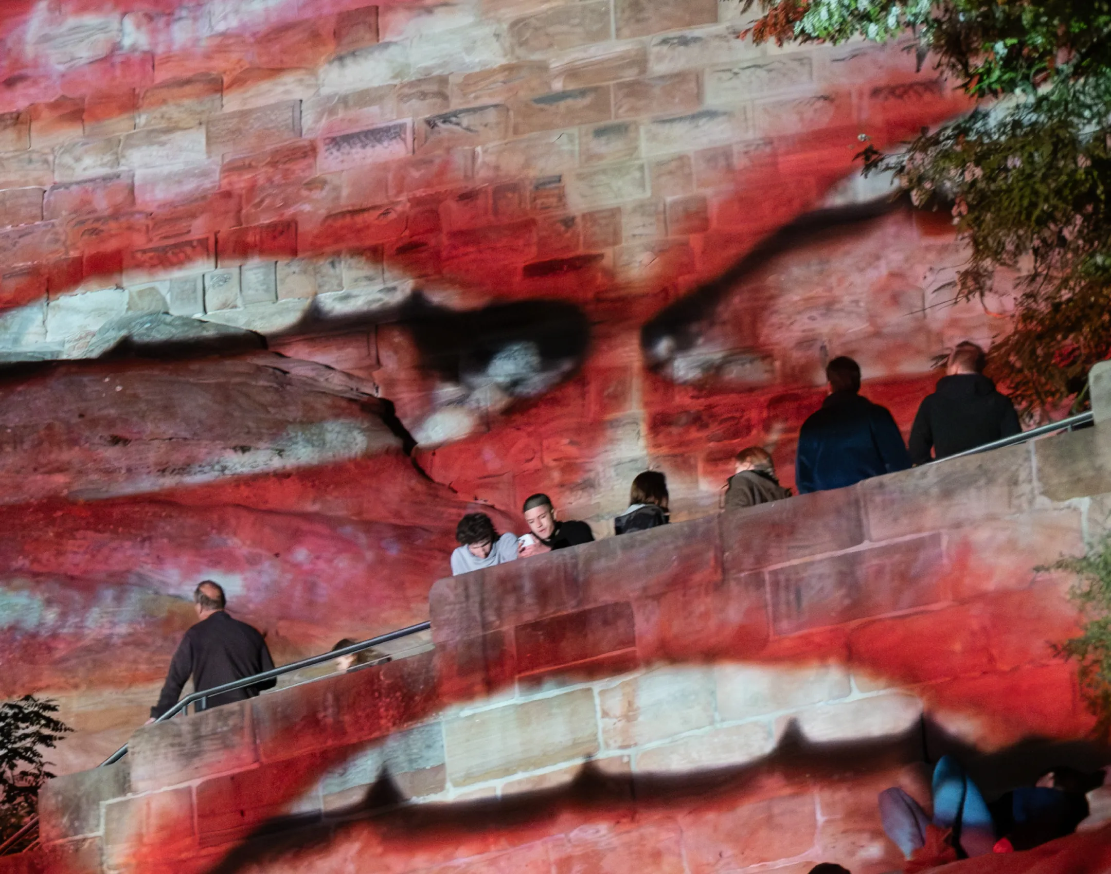 Bei der Blauen Nacht Nürnberg 2025 werdne Münder auf die Kaiserburg projiziert, man sieht Pesonen, die auf der Burg stehen