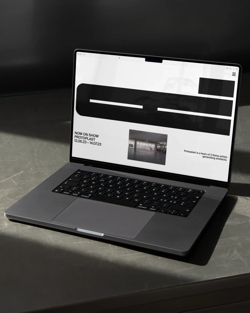 Laptop auf eisenem Tisch: auf dem Bildschirm moderne Website mit großer bolder Typografie und spannungsvollem Layout