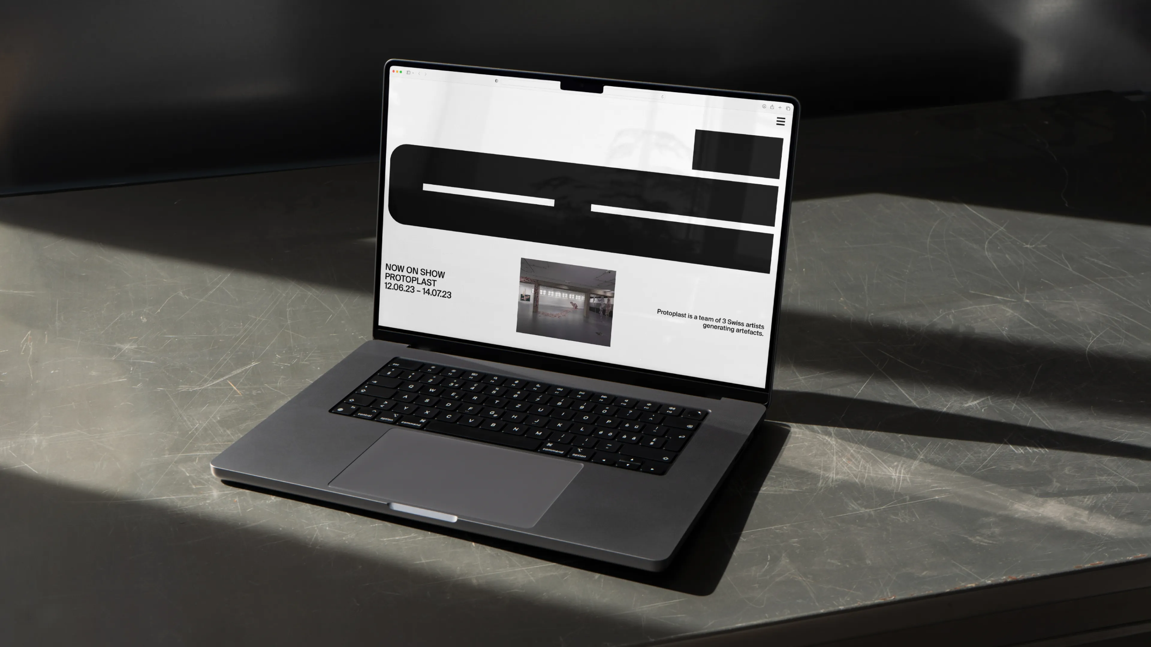 Laptop auf eisenem Tisch: auf dem Bildschirm moderne Website mit großer bolder Typografie und spannungsvollem Layout