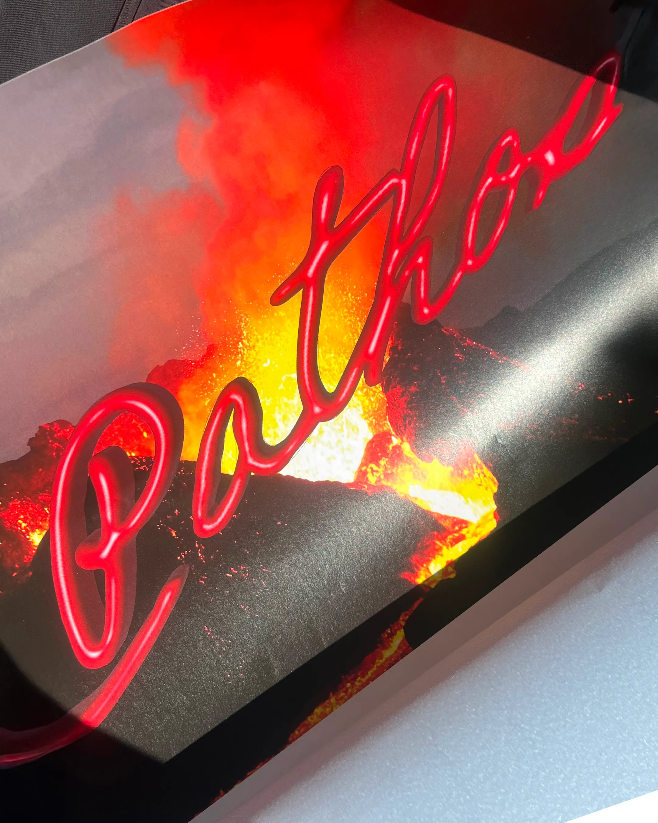 Detailaufnahme einer Programmflyer-Vorderseite mit den Pathos-Schriftzug in rotem Lava-Stil auf Vulkanhintergrund